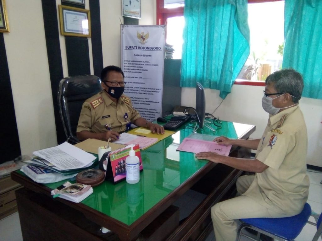 Camat Malo, Djamari SSos MM, saat disodori hasil monitoring kesiapan desa-desa dalam upaya pencegahan Covid-19 oleh Kasi Kesra Anang Setyo SE.